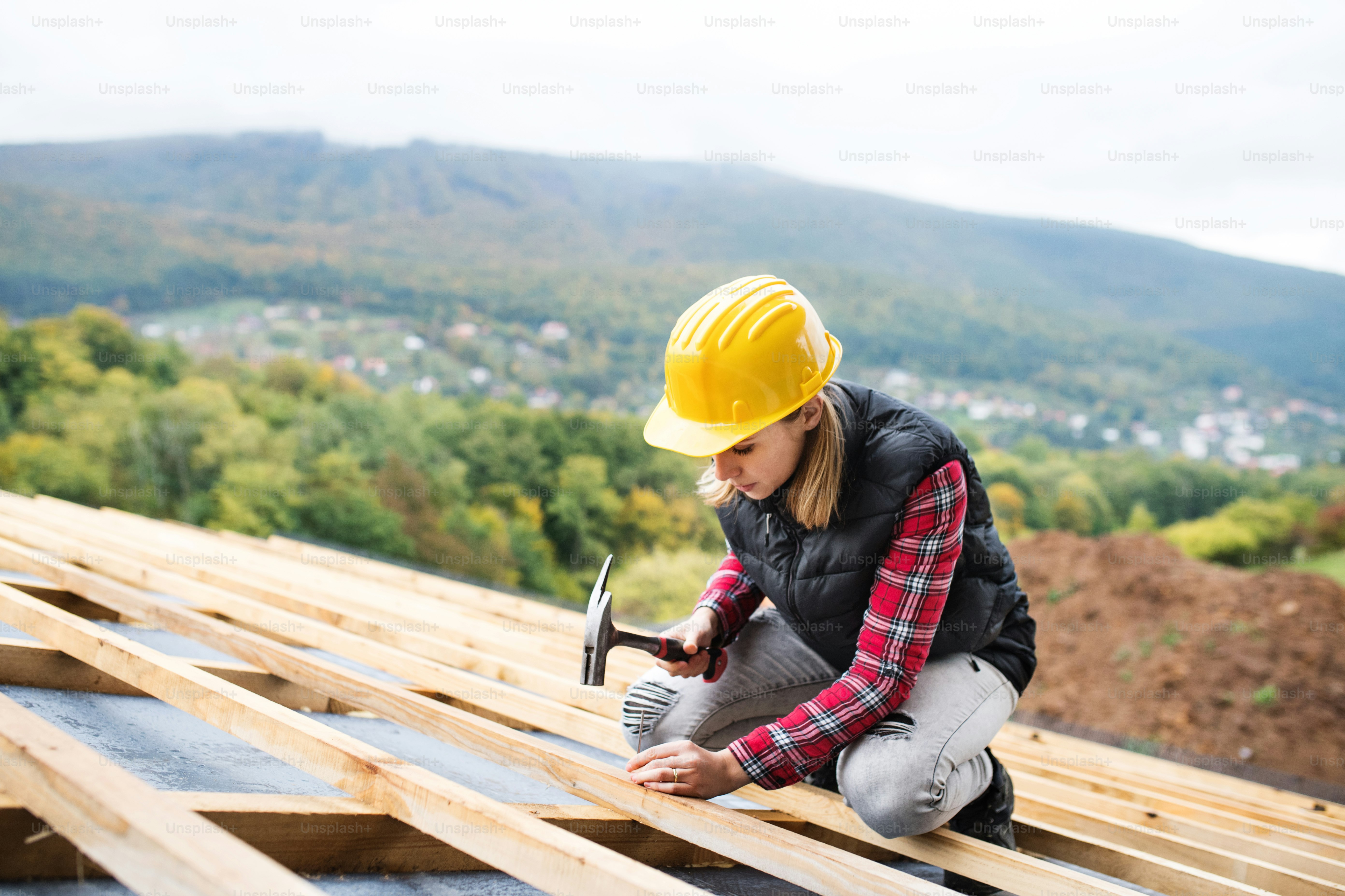 Female worker on the building site. Young woman working as a roofer. House construction